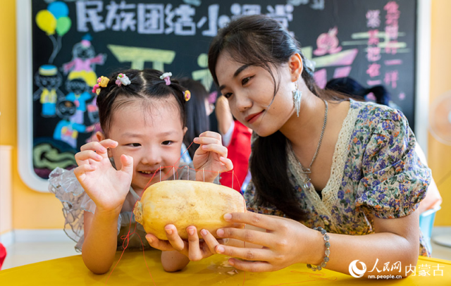 8月3日，内蒙古呼和浩特市玉泉区梁山街社区居民在“我们的节日·七夕”志愿服务活动现场体验“穿针乞巧”。丁根厚摄