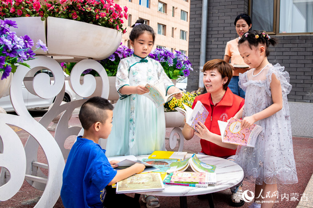 8月3日，内蒙古呼和浩特市玉泉区梁山街社区新时代文明实践站的志愿者在指导社区居民体验七夕晒书。丁根厚摄